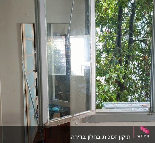חלון עץ עם זכוכית שהתנתק ממקומו בתהליך תיקון או החלפה
